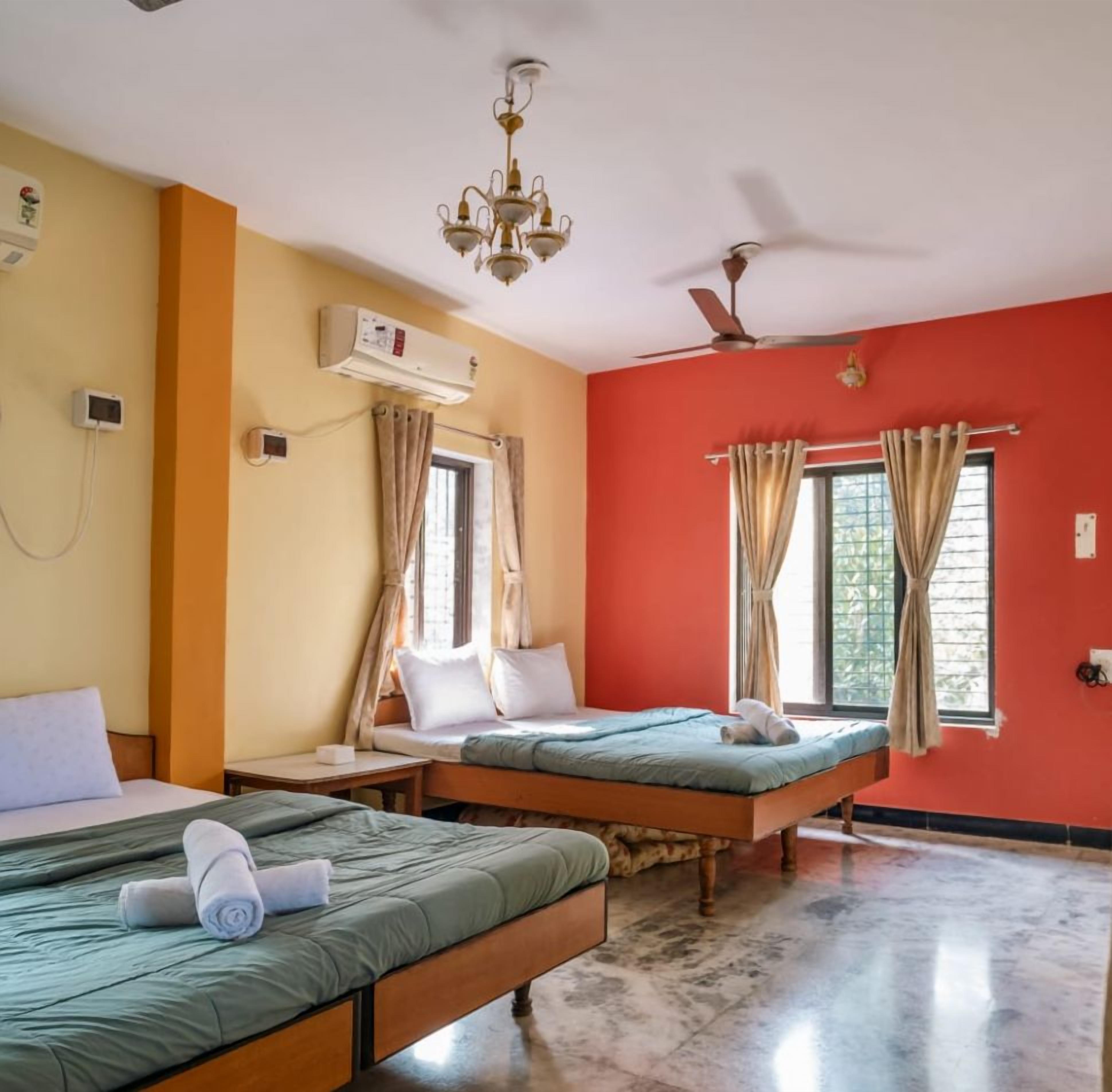 A hotel room with two beds, a ceiling fan, an air conditioning unit, and a chandelier.