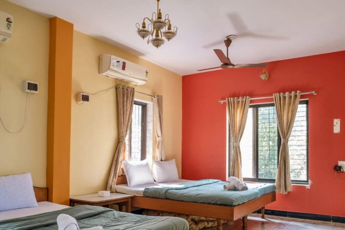 A hotel room with two beds, a ceiling fan, an air conditioning unit, and a chandelier.