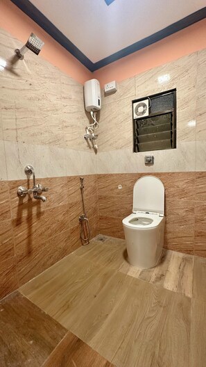 A bathroom with a toilet, a shower, and a hand dryer.