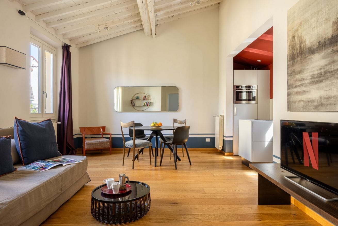 A modern living room with a sofa, coffee table, and a dining area with chairs and a table.
