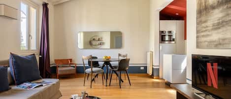 A modern living room with a sofa, coffee table, and a dining area with chairs and a table.