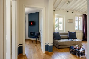 A living room with a sofa, a television, and a coffee table. - The Nerli Edit by Maison Florence (Florence)