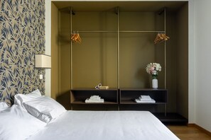 A hotel room with a bed, a wardrobe with shelves, and a wall with a leaf pattern. - The Nerli Edit by Maison Florence (Florence)
