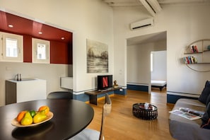 A modern living space with a dining area, a seating area with a sofa, a coffee table, and a bookshelf. - The Nerli Edit by Maison Florence (Florence)