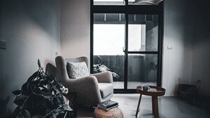 A modern living room with a large sliding glass door leading to an outdoor area, a comfortable armchair, a small round table, and a potted plant. - leesu (Hualien County)