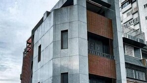 Un immeuble à plusieurs étages doté d’une architecture moderne, caractérisé par une combinaison de béton et de briques.