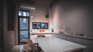 Une cuisine moderne dotée d’un grand îlot central, d’un coin repas avec une table et des chaises, et offrant une vue sur l’extérieur grâce à une fenêtre.