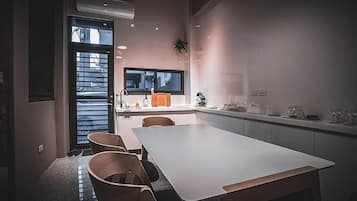 Eine moderne Küche mit einer großen Kochinsel, einem Essbereich mit Tisch und Stühlen sowie einem Fenster mit Jalousien.
