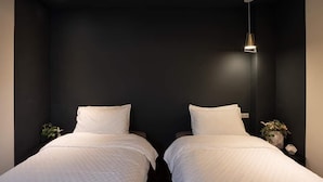 A room with two beds, a dark wall, and a pendant light. - leesu (Hualien County)