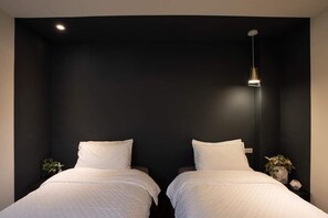 Een kamer met twee bedden, een donkere muur en een hanglamp.