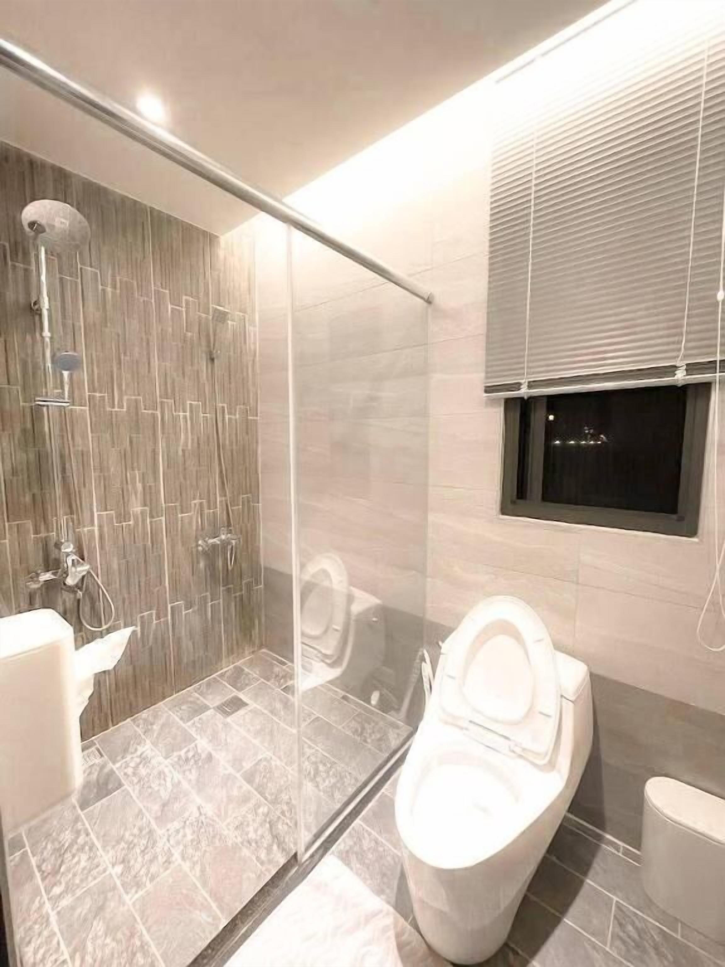 A modern bathroom with a glass-enclosed shower, a toilet, and a bidet.