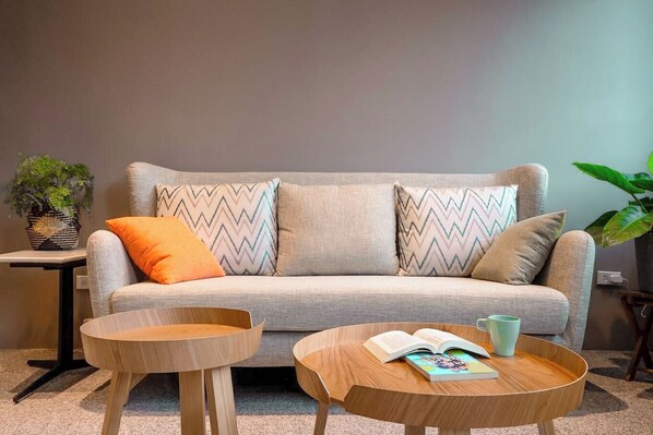 A modern living room with a grey sofa, two wooden side tables, and a book on one of the tables. - leesu (Hualien City)