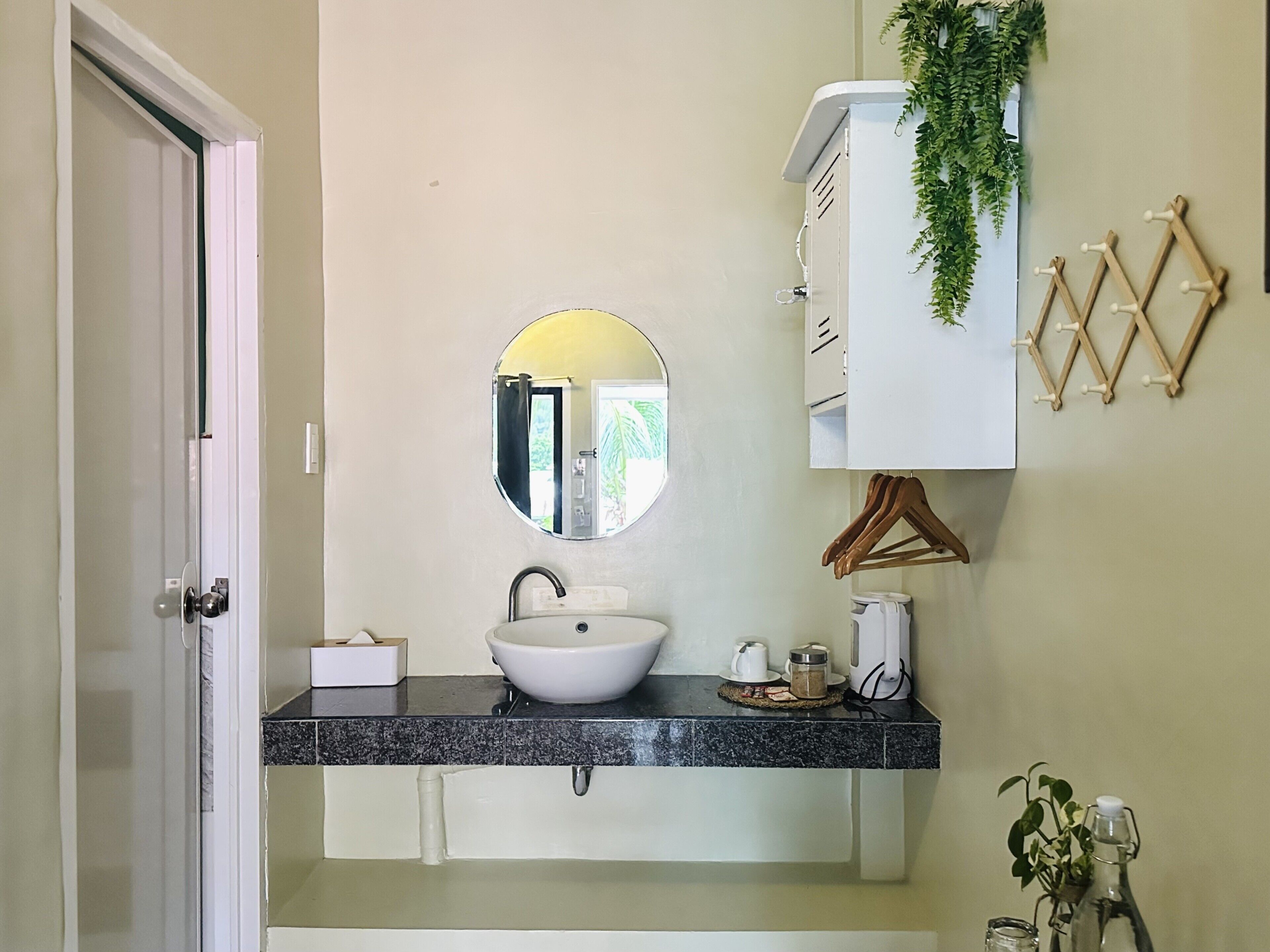 A bathroom with a white sink, a mirror, a towel rack, and a door.