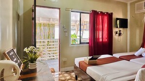 Quarto de hotel com cama, escrivaninha com computador, televisão e janela com cortinas.