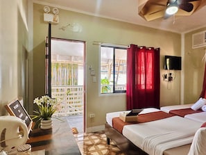 A hotel room with a bed, a desk with a computer, a TV, and a window with curtains. - Panari Lodge El Nido  (El Nido)