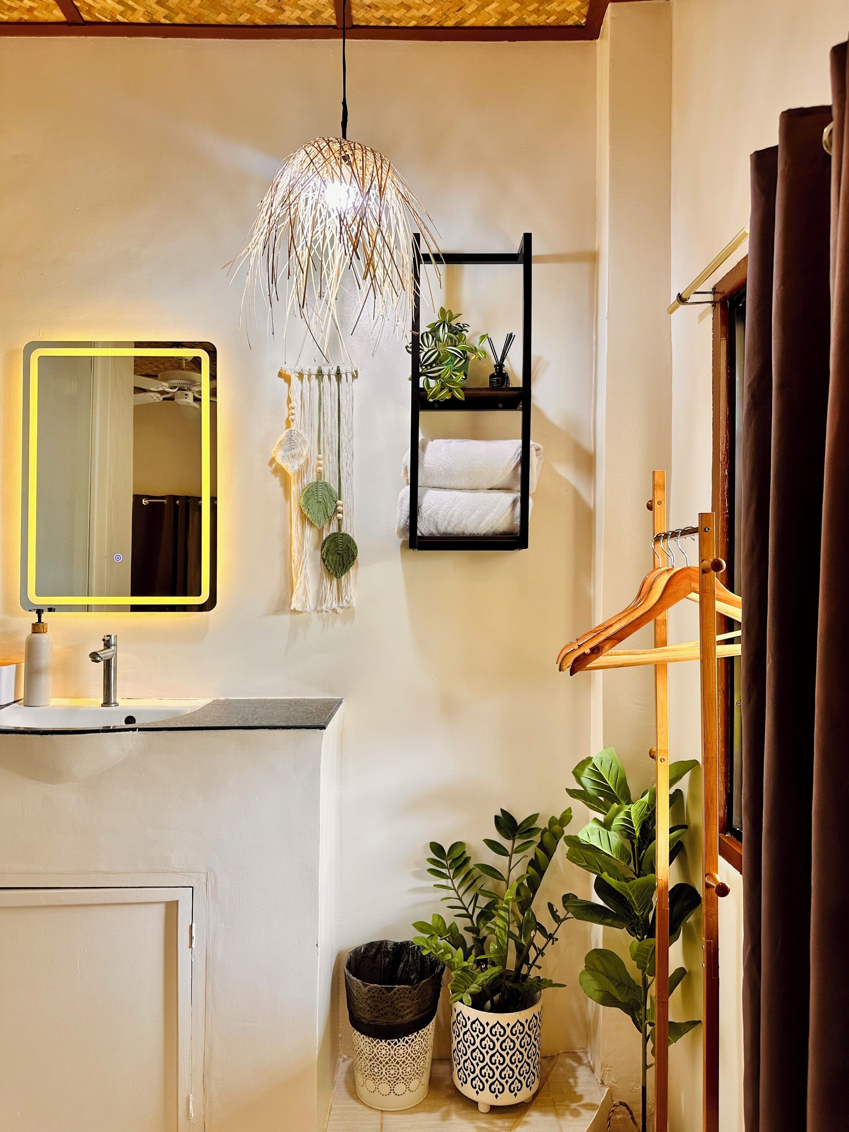 A bathroom with a mirror, a hanging light fixture, a towel rack, and a wooden drying rack.