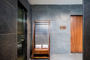 A room with a wooden wardrobe, a small wooden bench with towels, and a wall-mounted towel warmer.