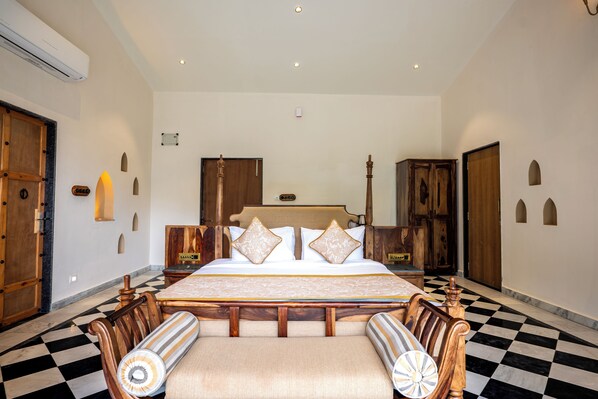 A hotel room with a large bed, wooden furniture, and a checkered floor.