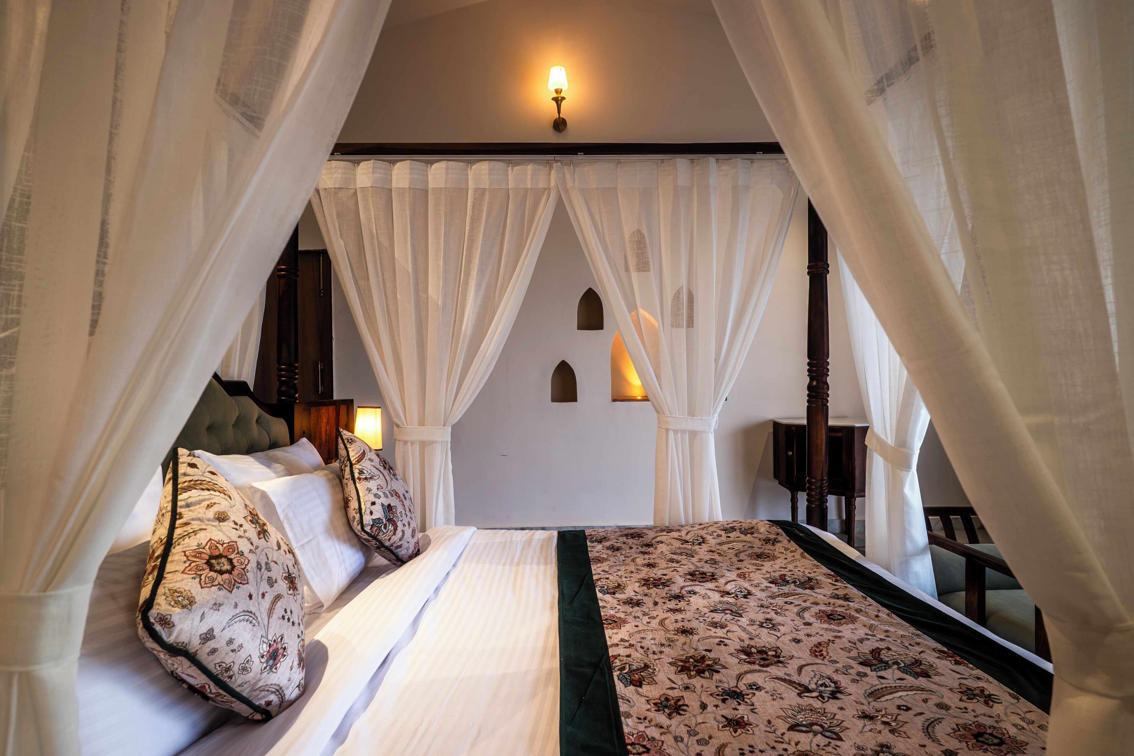 A bedroom with a canopy bed, a patterned bedspread, and a view of the night sky.