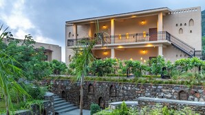 A multi-story building with a stone staircase leading to a balcony. - The Talhati (Kumbhalgarh)