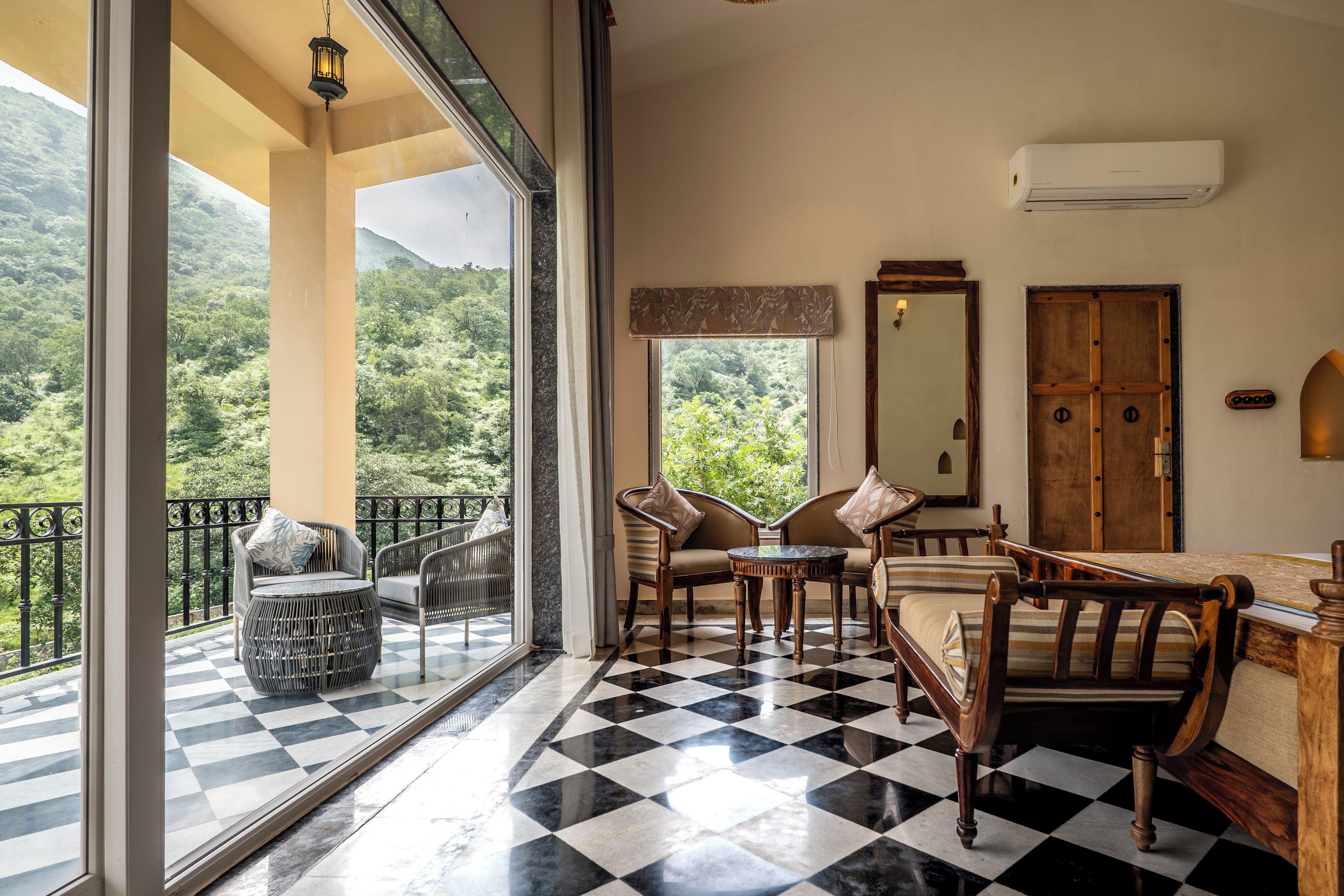Una habitación con piso a cuadros, un balcón con vista a la vegetación y una puerta de madera.