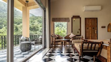 Una habitación con piso a cuadros, un balcón con vista a la vegetación y una puerta de madera.