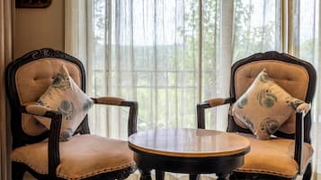 A room with two upholstered chairs with armrests, a small round table, and a checkered floor.
