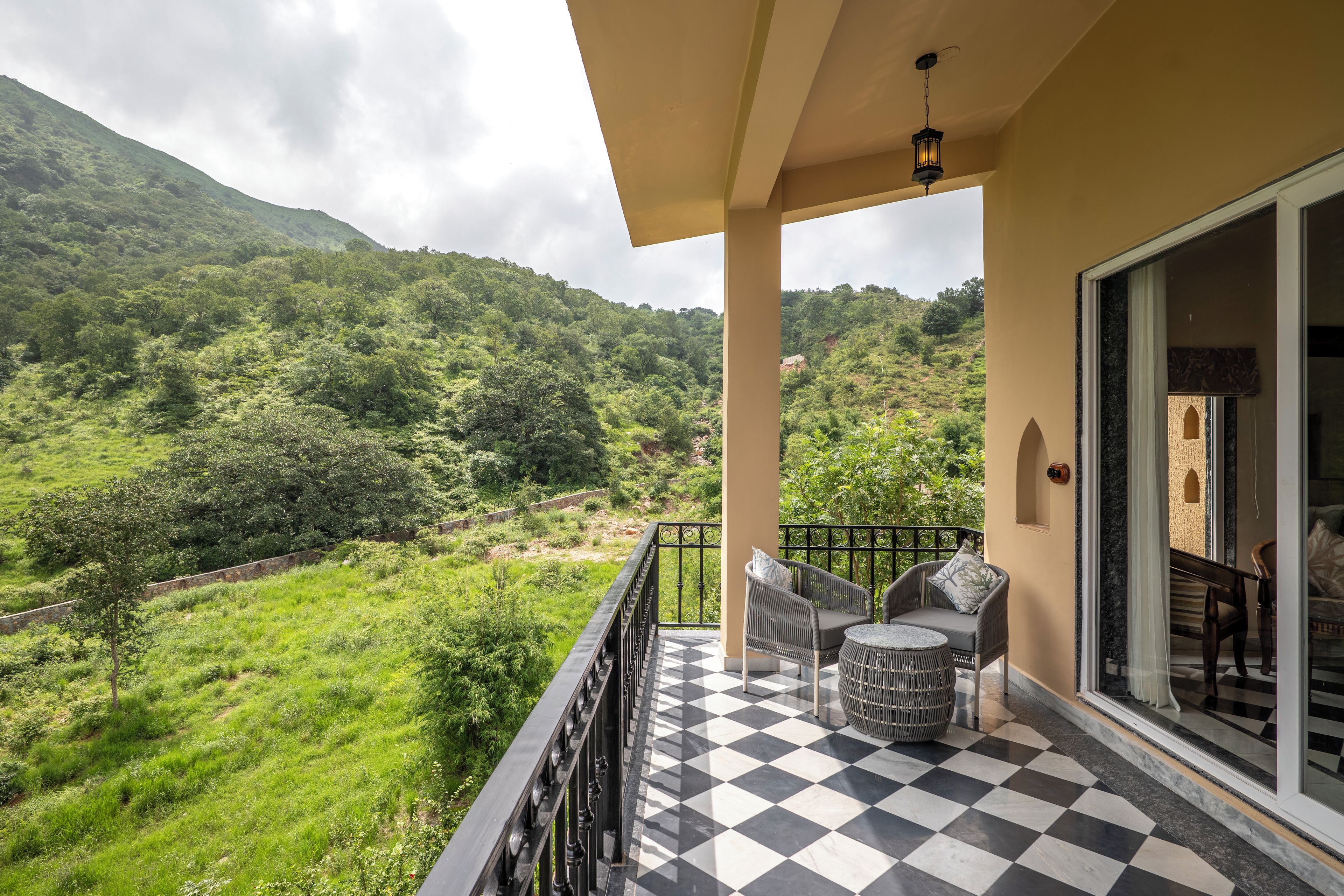 A balcony with a checkered floor, a wicker chair, and a table.
