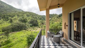 A balcony with a checkered floor, a wicker chair, and a table.