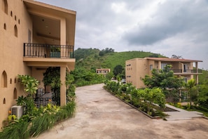 A residential area with multiple buildings, a paved pathway, and lush greenery.