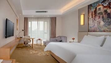 A hotel room with a large bed, a desk, a chair, a television, and a painting on the wall.
