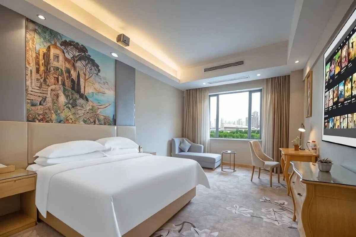 A hotel room with a large bed, a sofa, a small table, and a TV.