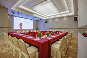 A conference room with a long table, chairs, and a presentation screen. - Vienna International Hotel (Changsha)
