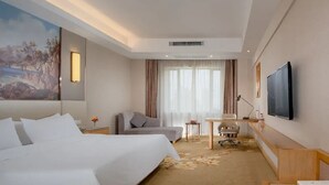 A hotel room with a bed, a desk, a chair, a television, and a painting on the wall. - Vienna International Hotel (Changsha)