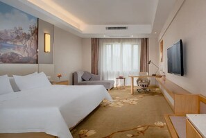 A hotel room with a bed, a desk, a chair, a television, and a painting on the wall. - Vienna International Hotel (Changsha)