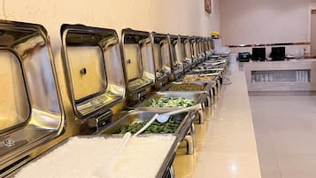 A buffet line with various food options, including rice, vegetables, and meats.