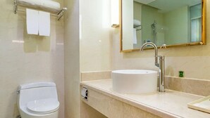 A bathroom with a toilet, sink, and mirror. - Vienna International Hotel (Changsha)