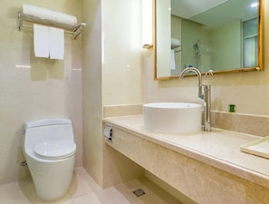 A bathroom with a toilet, sink, and mirror. - Vienna International Hotel (Changsha)