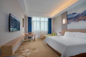 A hotel room with a bed, a desk, a chair, a TV, and a painting on the wall. - Vienna International Hotel (Changsha)