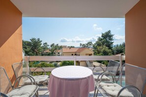 A balcony with a round table and chairs, overlooking a residential area with houses and trees. - Laidback Apartments - One Bedroom Apartment With Balcony and Sea View (Orebic)