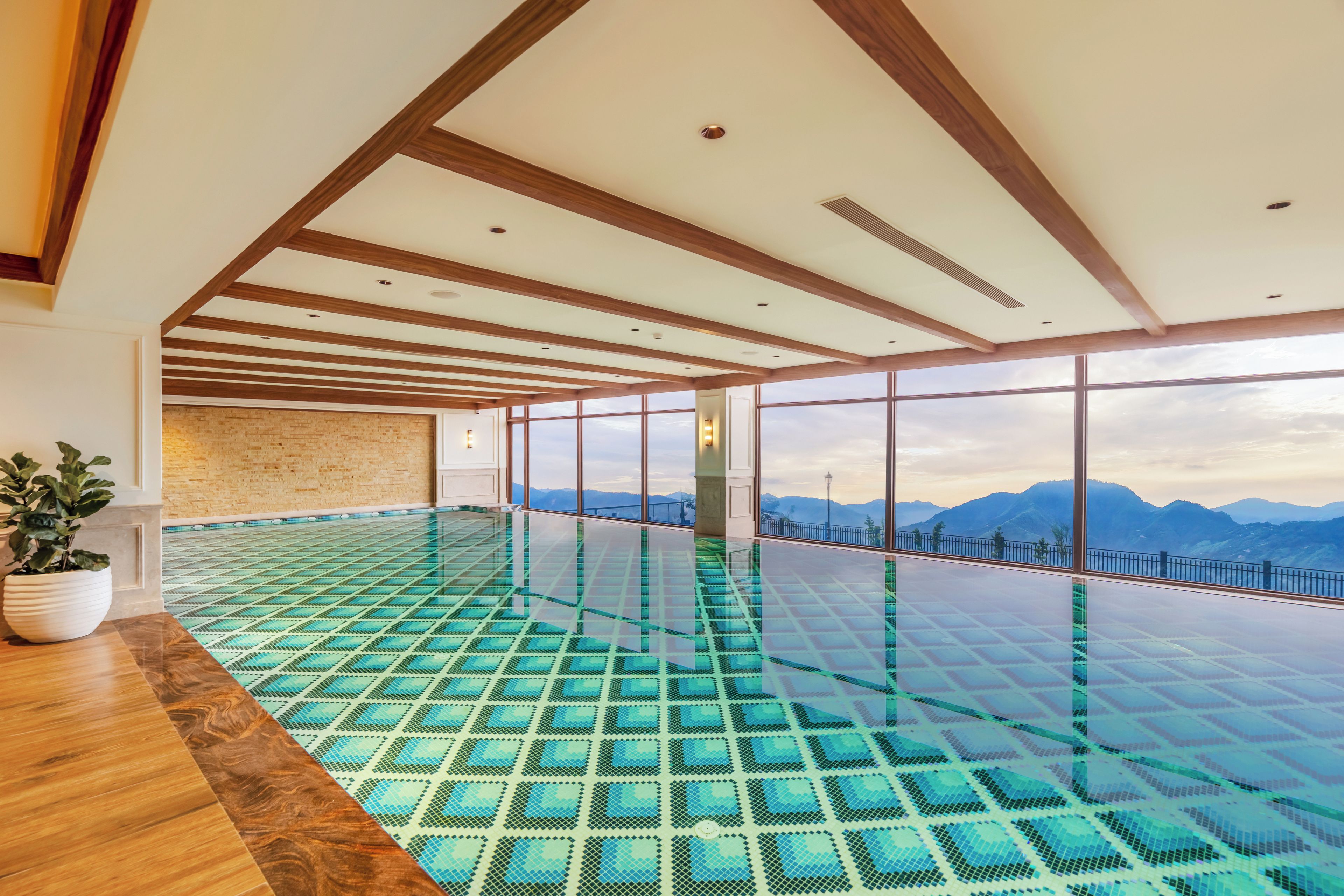 A spacious indoor swimming pool with a clear view of mountains through large windows.