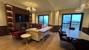 Een moderne woonkamer met een open haard, comfortabele zithoek, een eethoek en grote ramen.