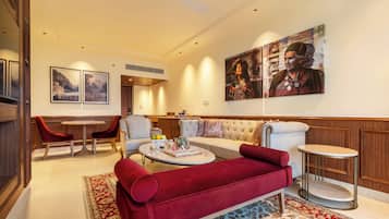 A well-lit living room with a red sofa, a round coffee table, and a dining area with chairs and a table.