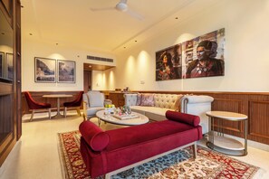 A well-lit living room with a red sofa, a round coffee table, and a dining area with chairs and a table. - Aurika Naldehra Shimla (Suni)