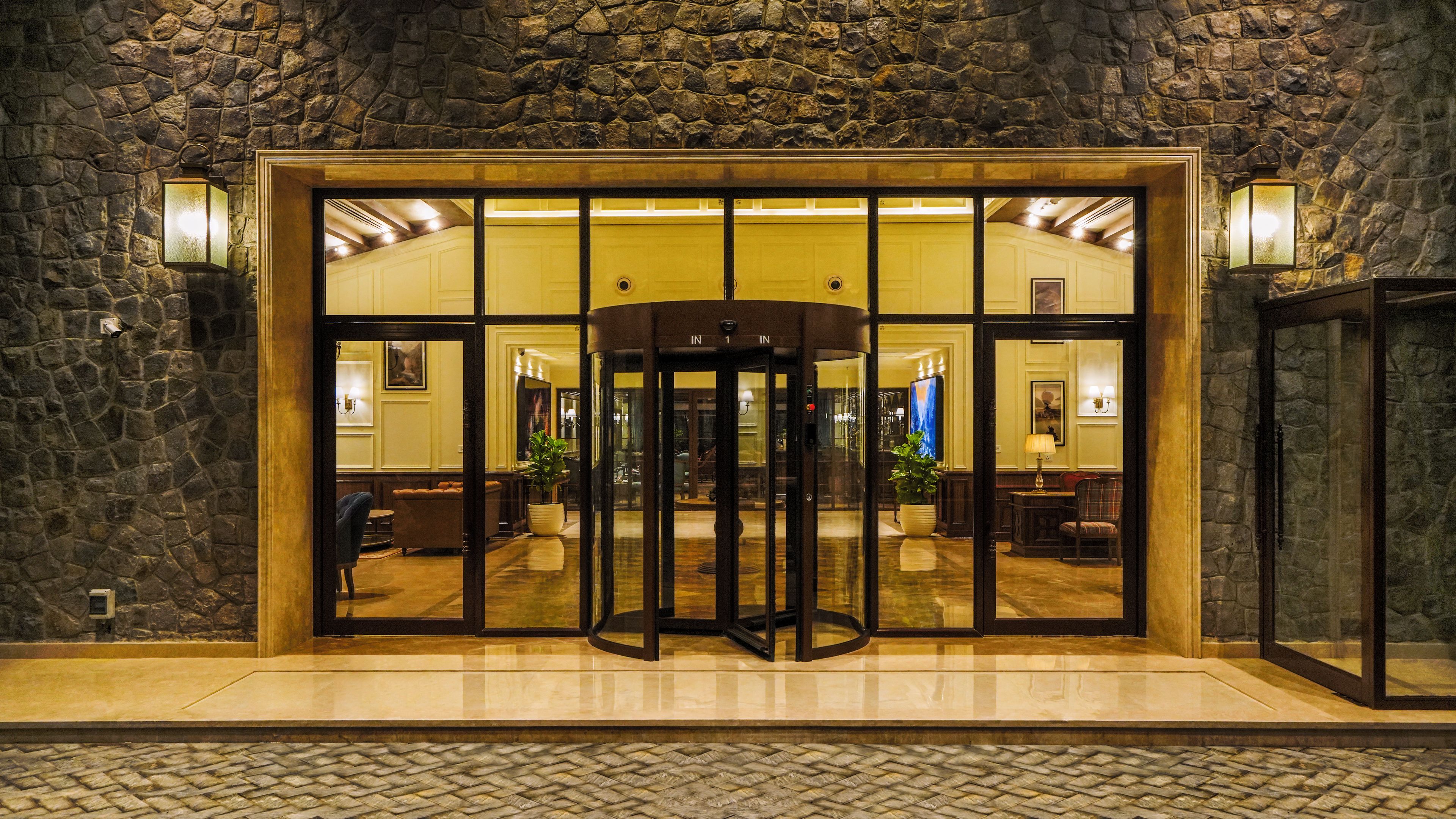 A lobby with a stone wall, a revolving door, and a reception area with seating.