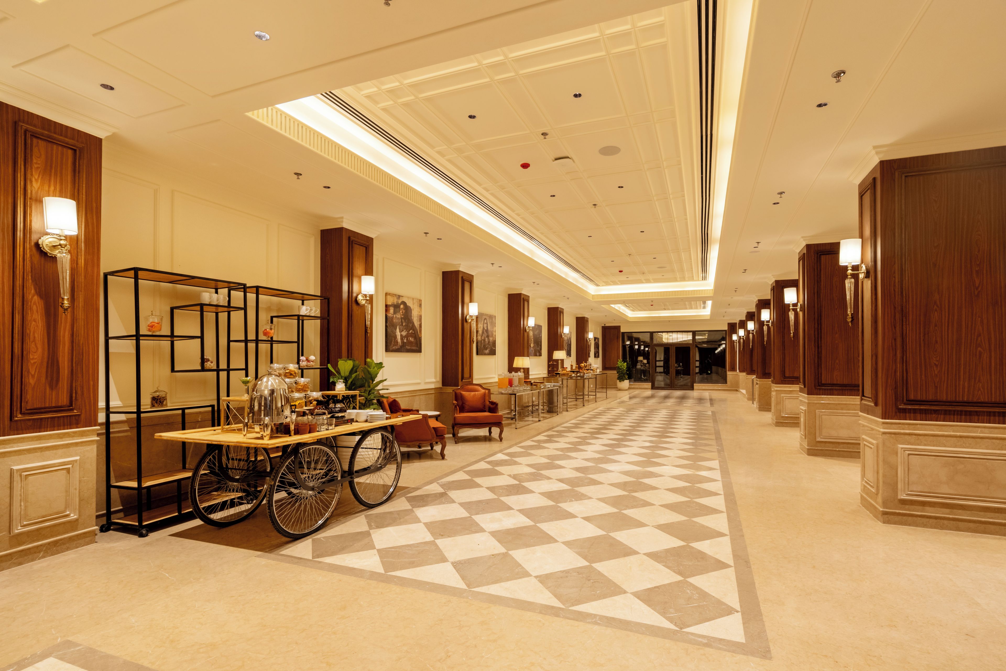 En hotellobby med ett rutmönstrat golv, en kaffevagn och en rullstol.