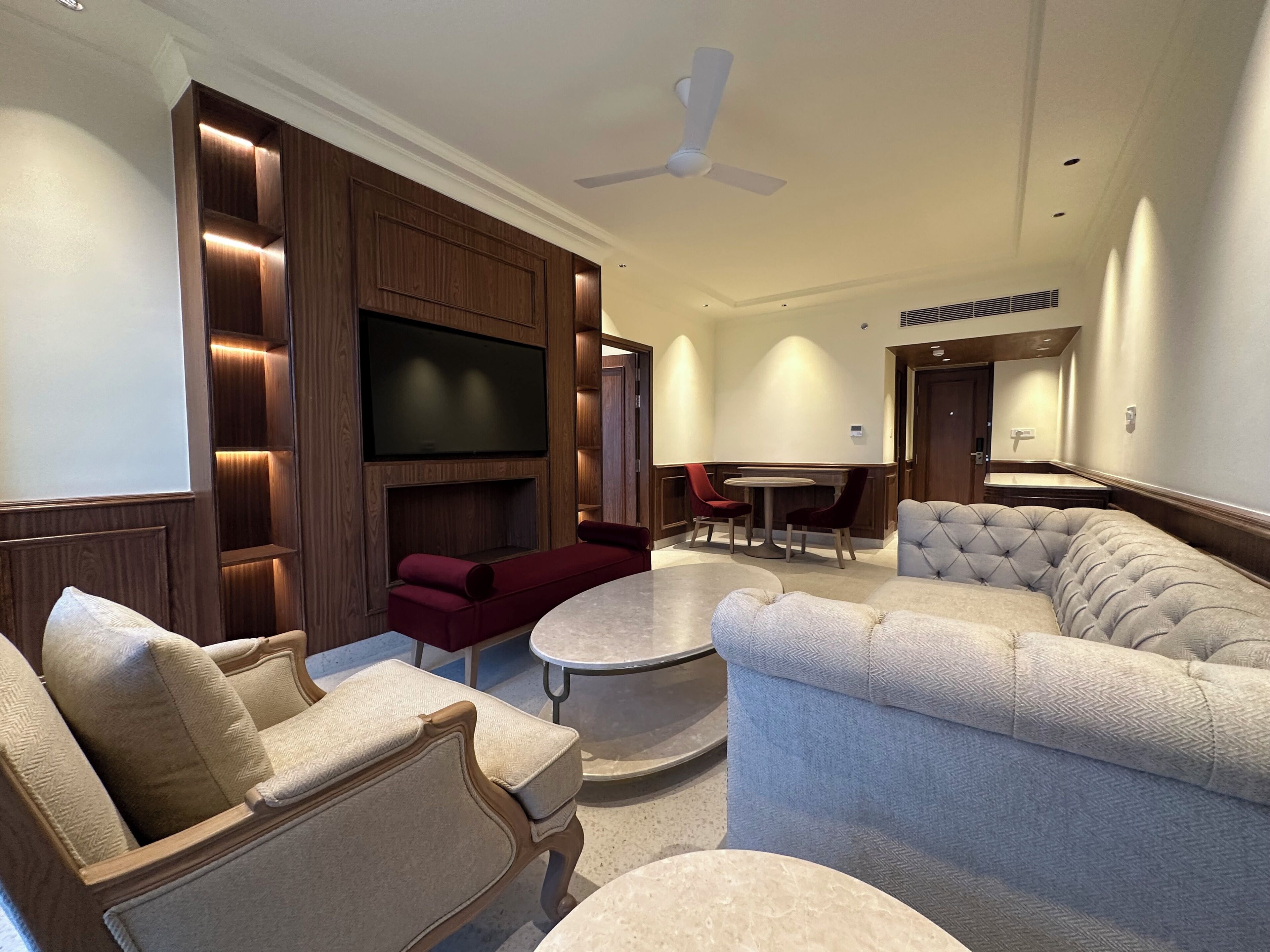 A modern living room with a flat-screen TV, comfortable seating, a ceiling fan, and a dining area.