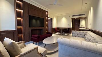 A modern living room with a flat-screen TV, comfortable seating, a ceiling fan, and a dining area.