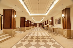 A hotel hallway with a checkered floor, wooden doors, and a long corridor leading to a reception area. - Aurika Naldehra Shimla (Suni)