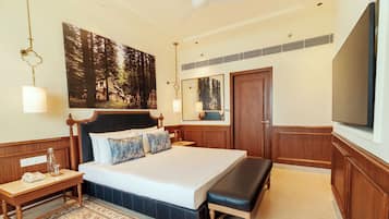 A hotel room with a large bed, a bedside table with a lamp, a mirror, a television, and a large painting on the wall.